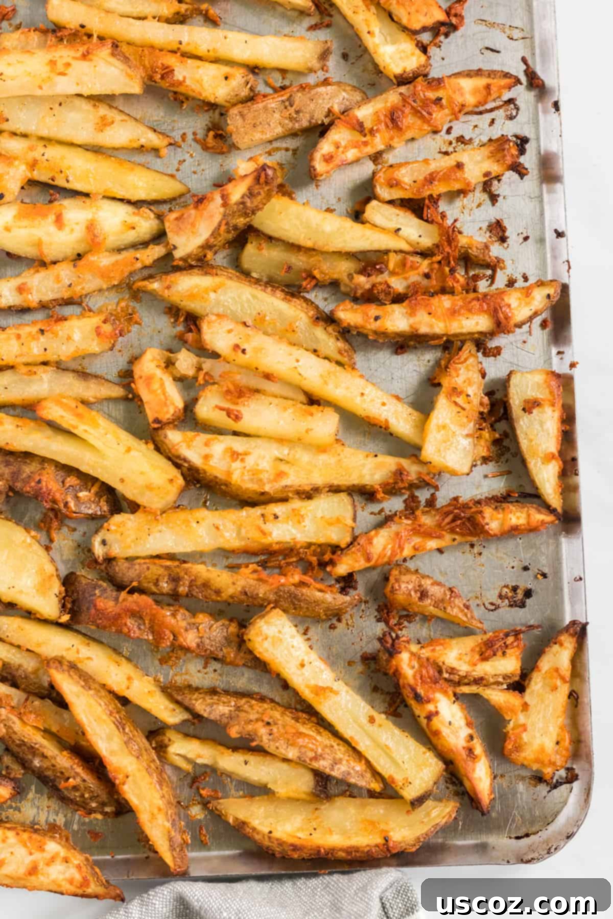 Garlic Parmesan Baked Potato Wedges 10 A wider shot of perfectly baked and golden crispy potato wedges, generously coated with parmesan and spices, cooling on a baking sheet, ready for serving.
