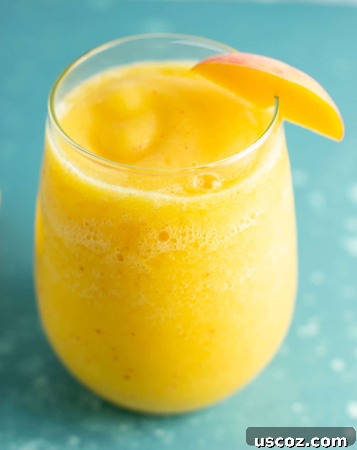 A close-up of a refreshing peach moscato slushie, garnished with a fresh peach slice, illustrating an ideal frozen peach drink for summer.