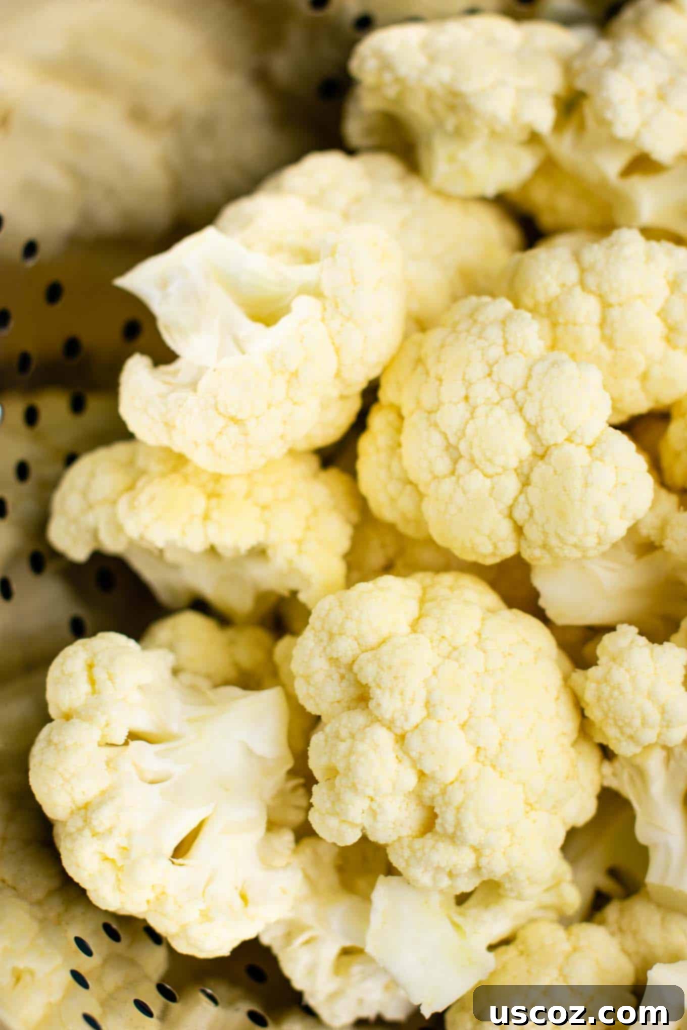 Perfectly Steamed Cauliflower 5 Close-up of fresh cauliflower florets placed inside a metal colander, ready for steaming.
