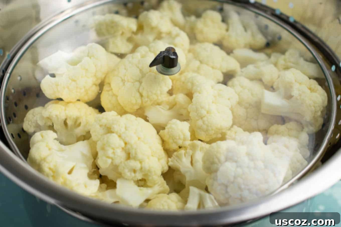 Perfectly Steamed Cauliflower 6 A simple setup for steaming cauliflower: a metal colander filled with florets placed in a large pot, with a lid on top to trap steam.