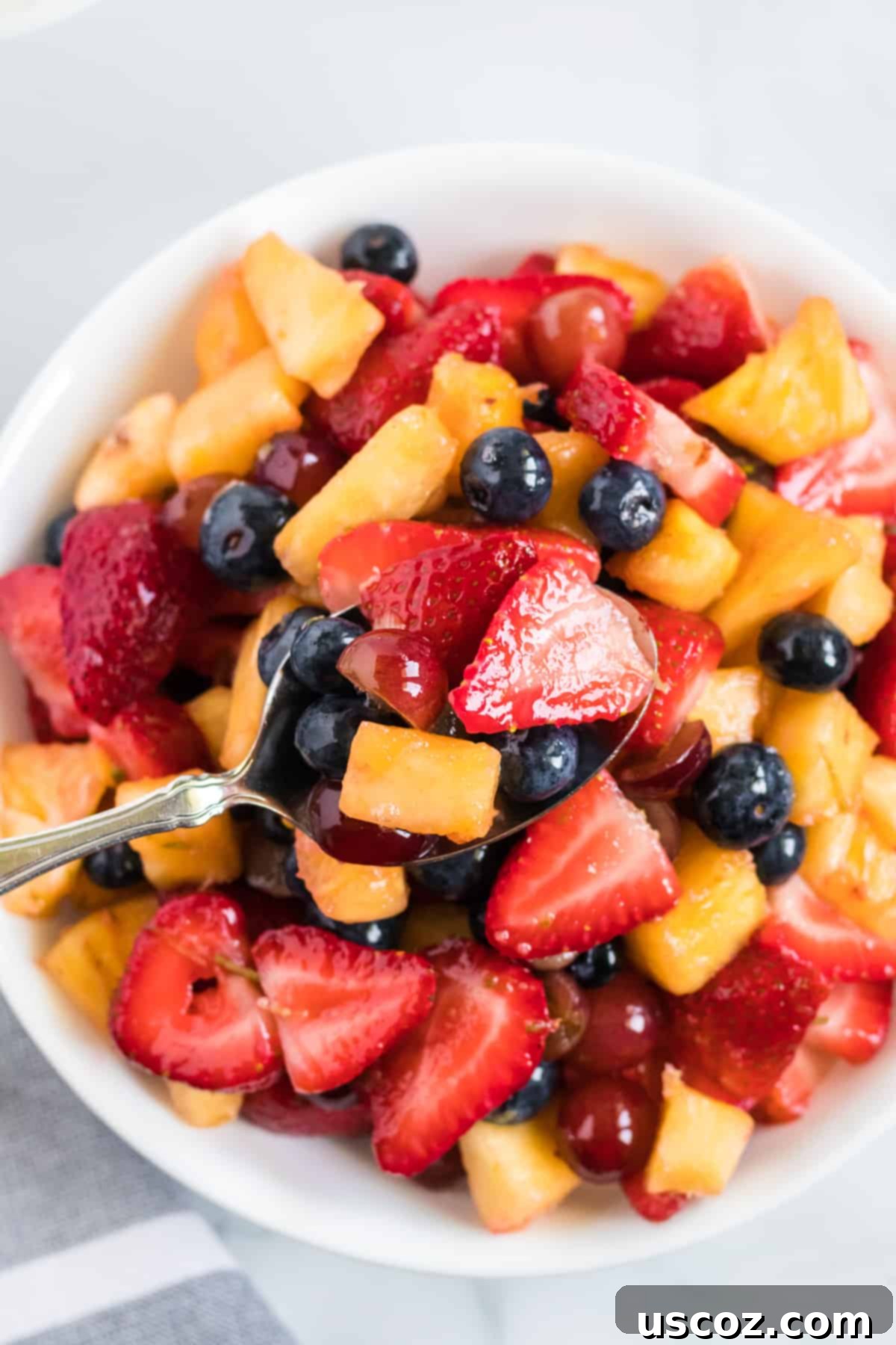 Vibrant Fruit Medley 8 spoon taking a serving of fruit salad from the dish