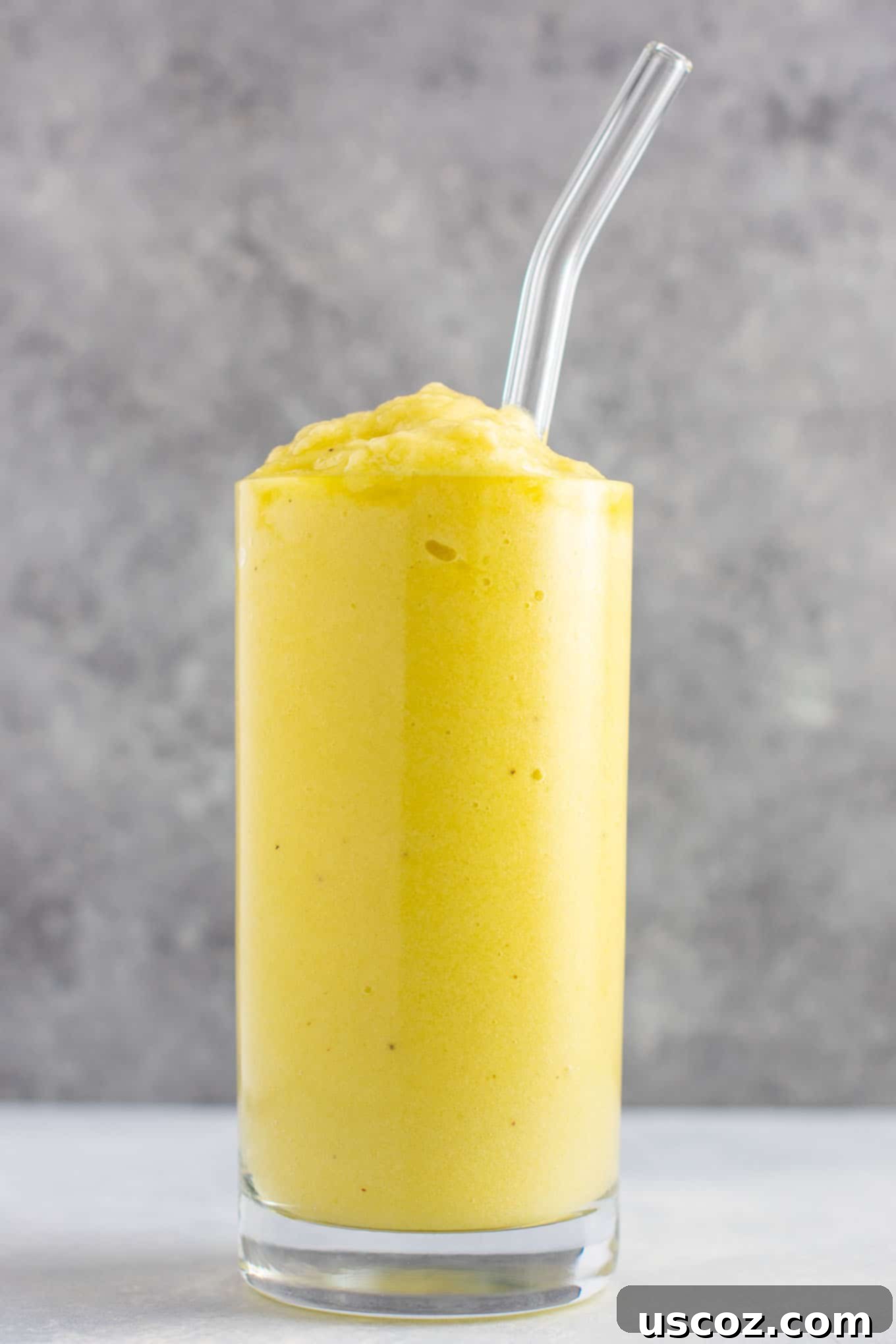 Pineapple Detox Blast 13 A close-up of a refreshing pineapple detox smoothie in a clear glass, with a focus on its smooth and thick texture, garnished with a pineapple wedge.