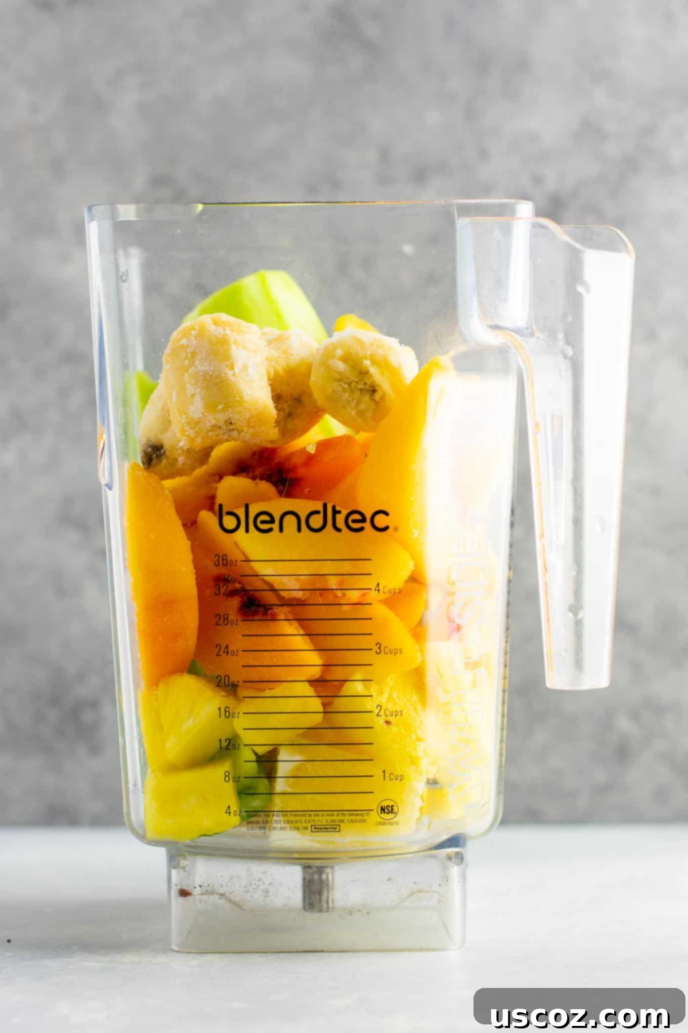 Pineapple Detox Blast 4 Close-up of all the fresh ingredients for a pineapple detox smoothie: whole pineapple, cucumbers, celery stalks, lemons, fresh ginger root, alongside frozen bananas and peaches.