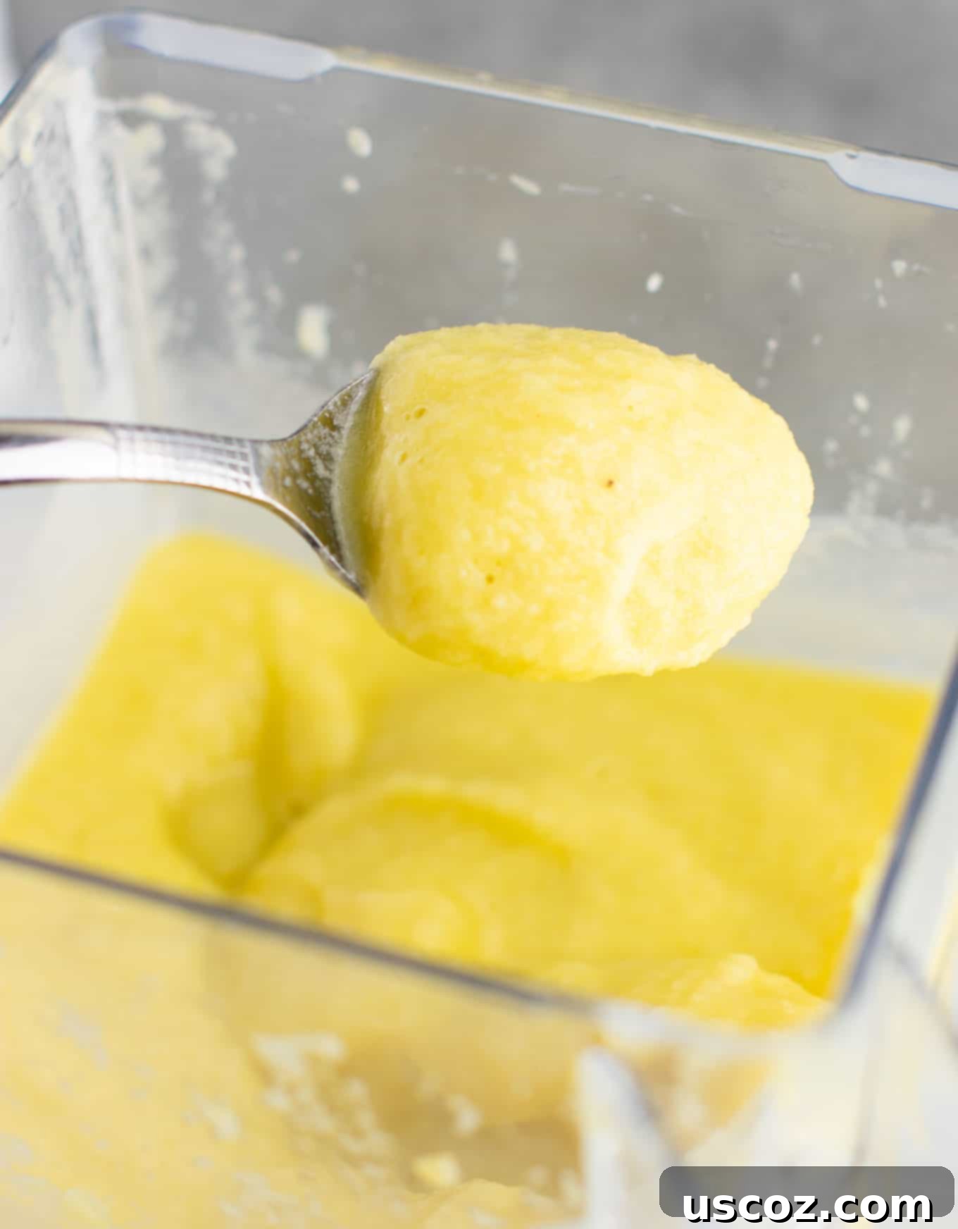 Pineapple Detox Blast 7 A spoon scooping a thick, creamy pineapple detox smoothie, highlighting its luxurious texture.