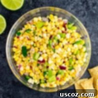 Zesty Corn Relish 7 Fresh corn salsa in a white bowl, garnished with cilantro, with a spoon nestled in the salsa, ready to be served.