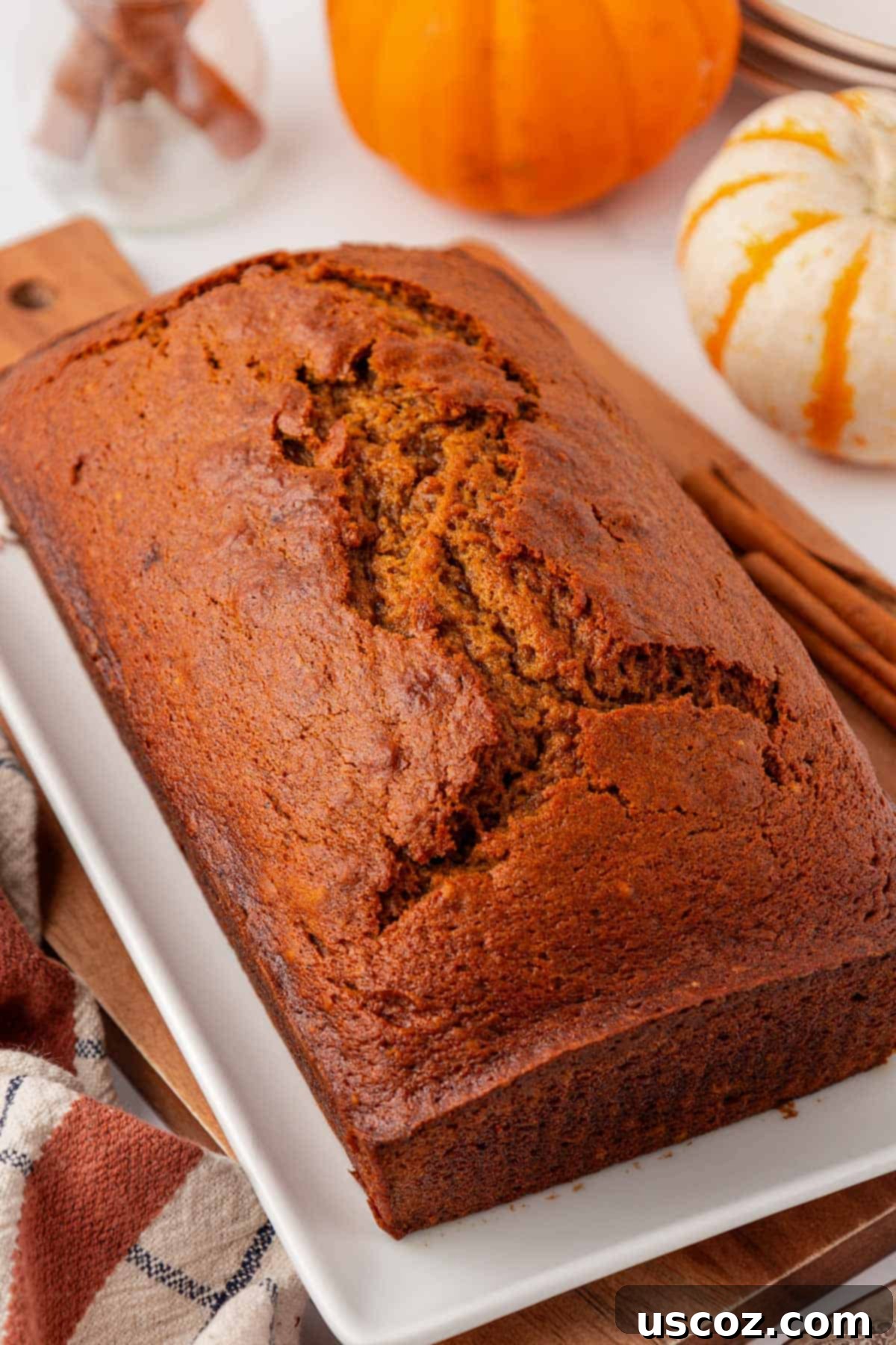 Perfectly baked, golden brown pumpkin bread on a cutting board, ready to be sliced