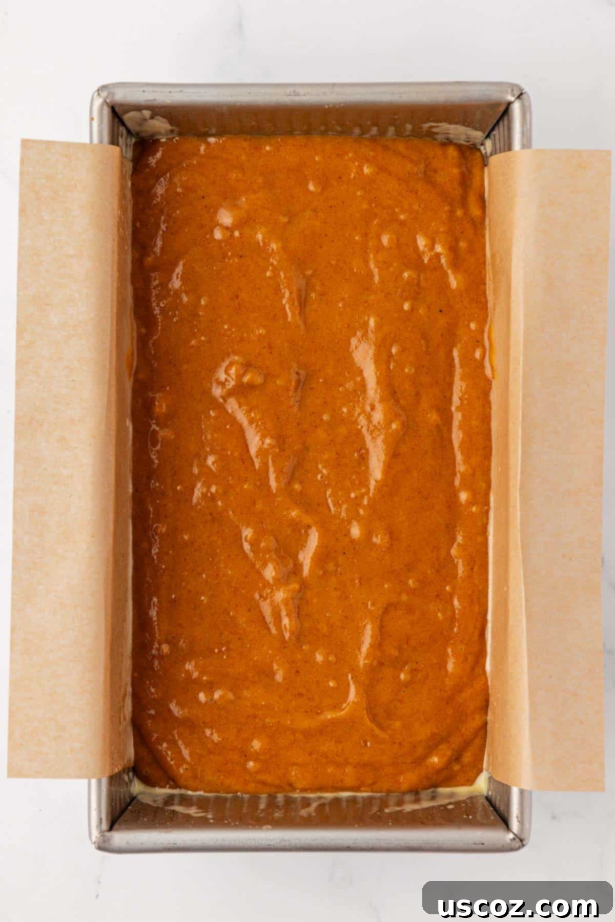 Pumpkin bread batter smoothly spread into a greased loaf pan