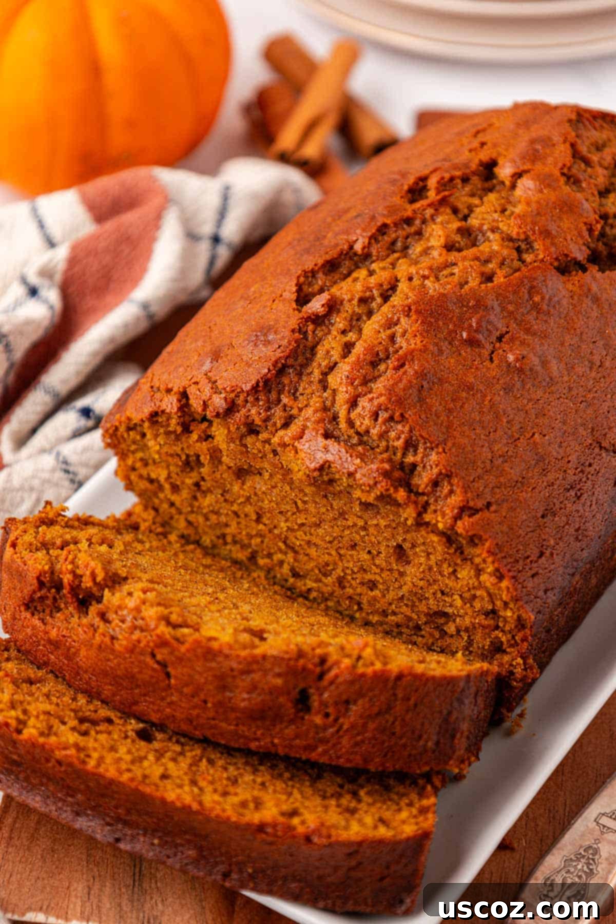 A whole pumpkin bread loaf, beautifully browned, placed on a wooden surface