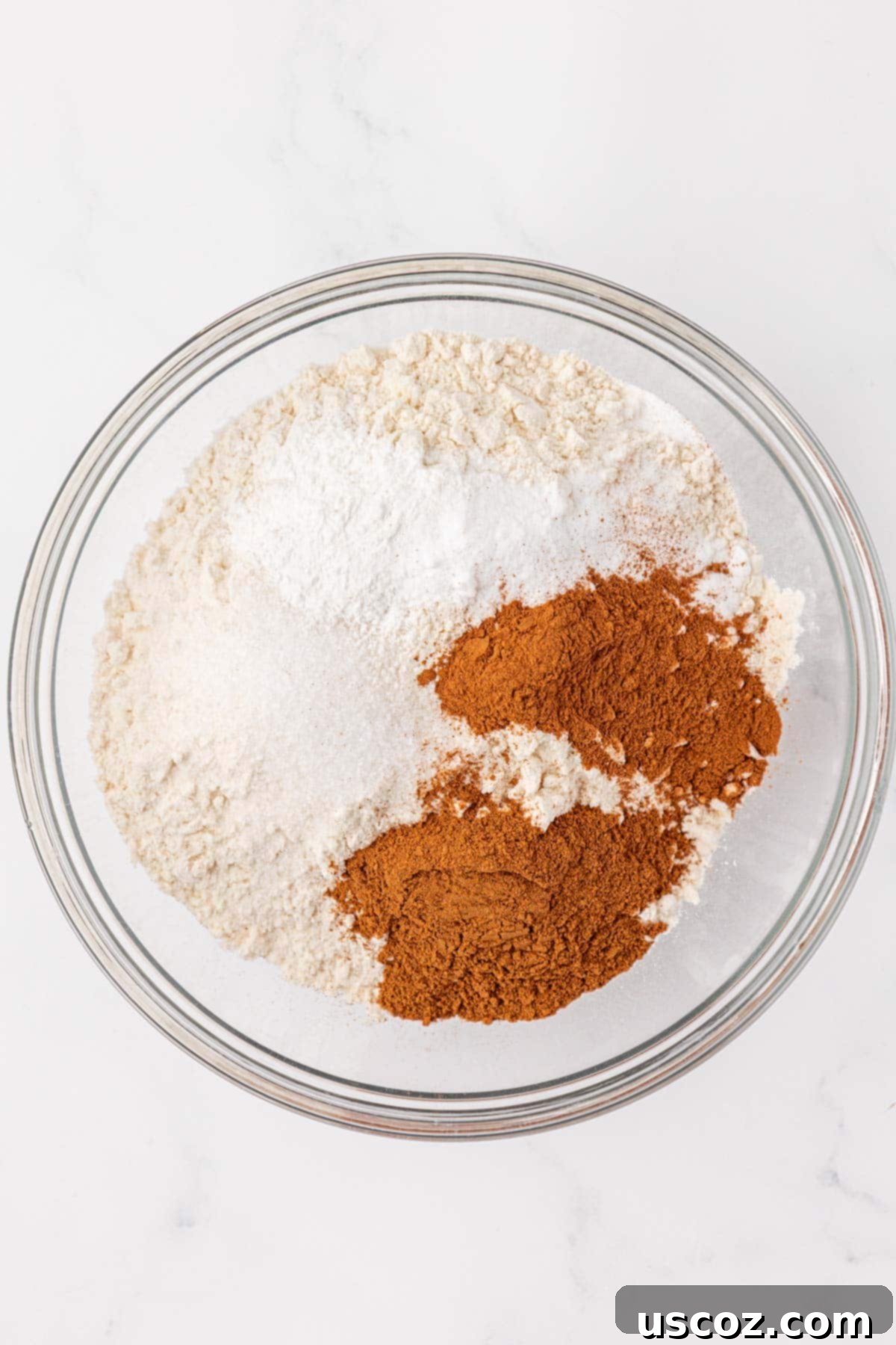 Dry ingredients for pumpkin bread, including flour and spices, in a mixing bowl before whisking