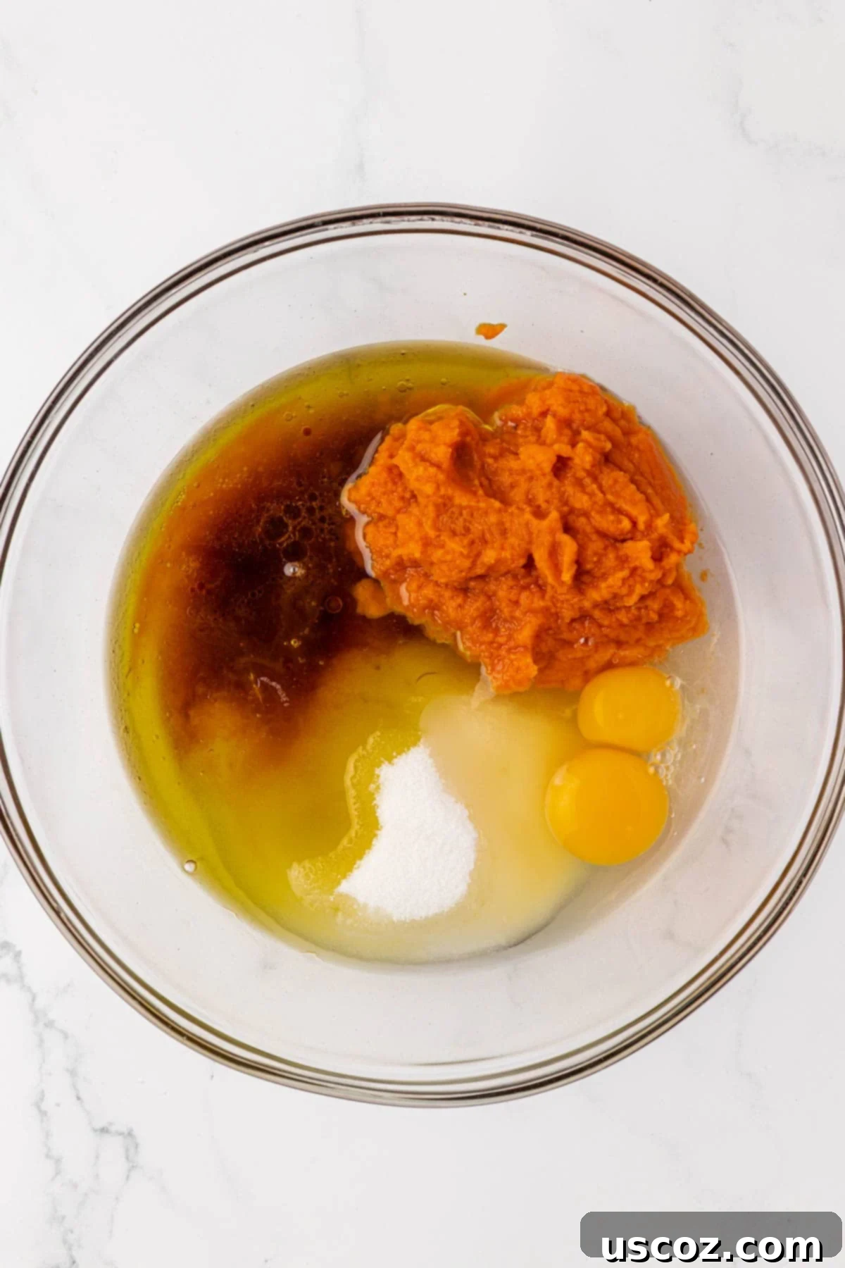 Wet ingredients for pumpkin bread, including pumpkin puree, oil, and eggs, in a mixing bowl
