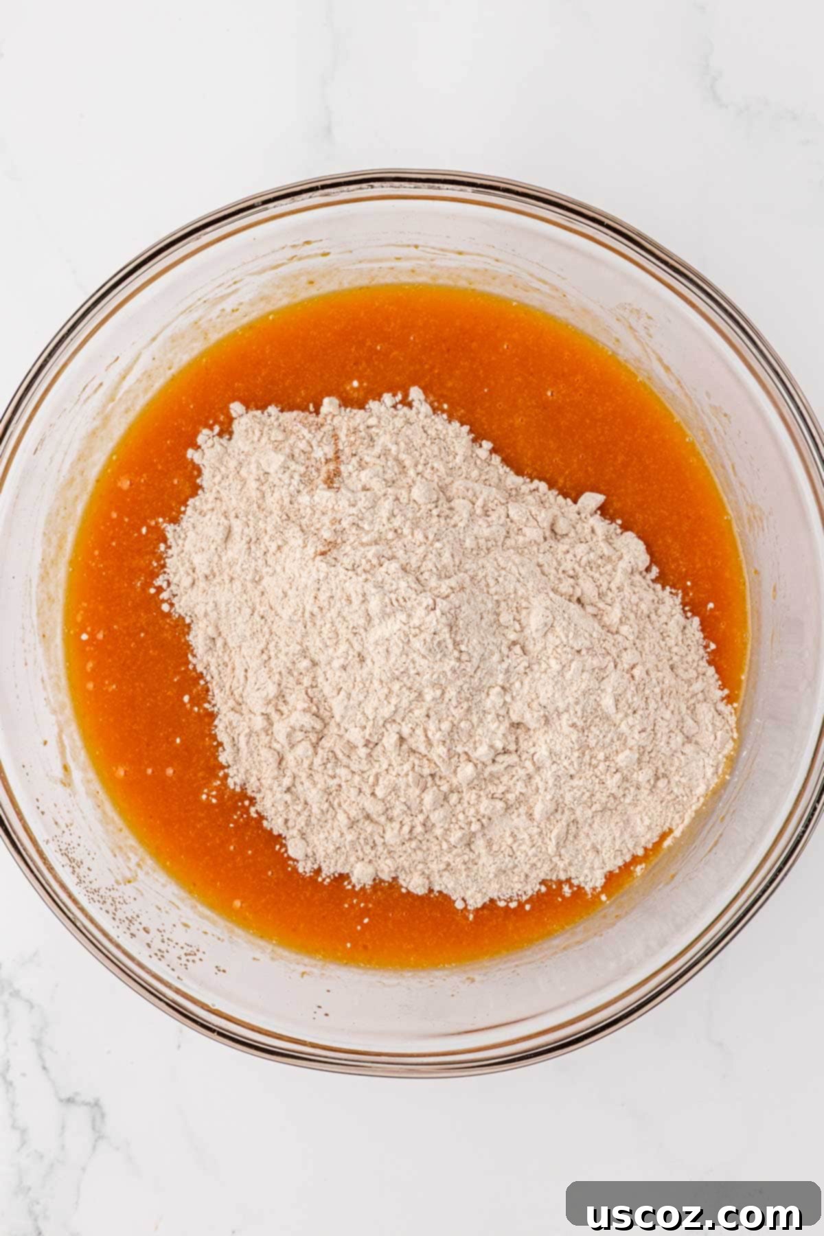 Adding the dry flour mixture into the wet pumpkin ingredients in a bowl