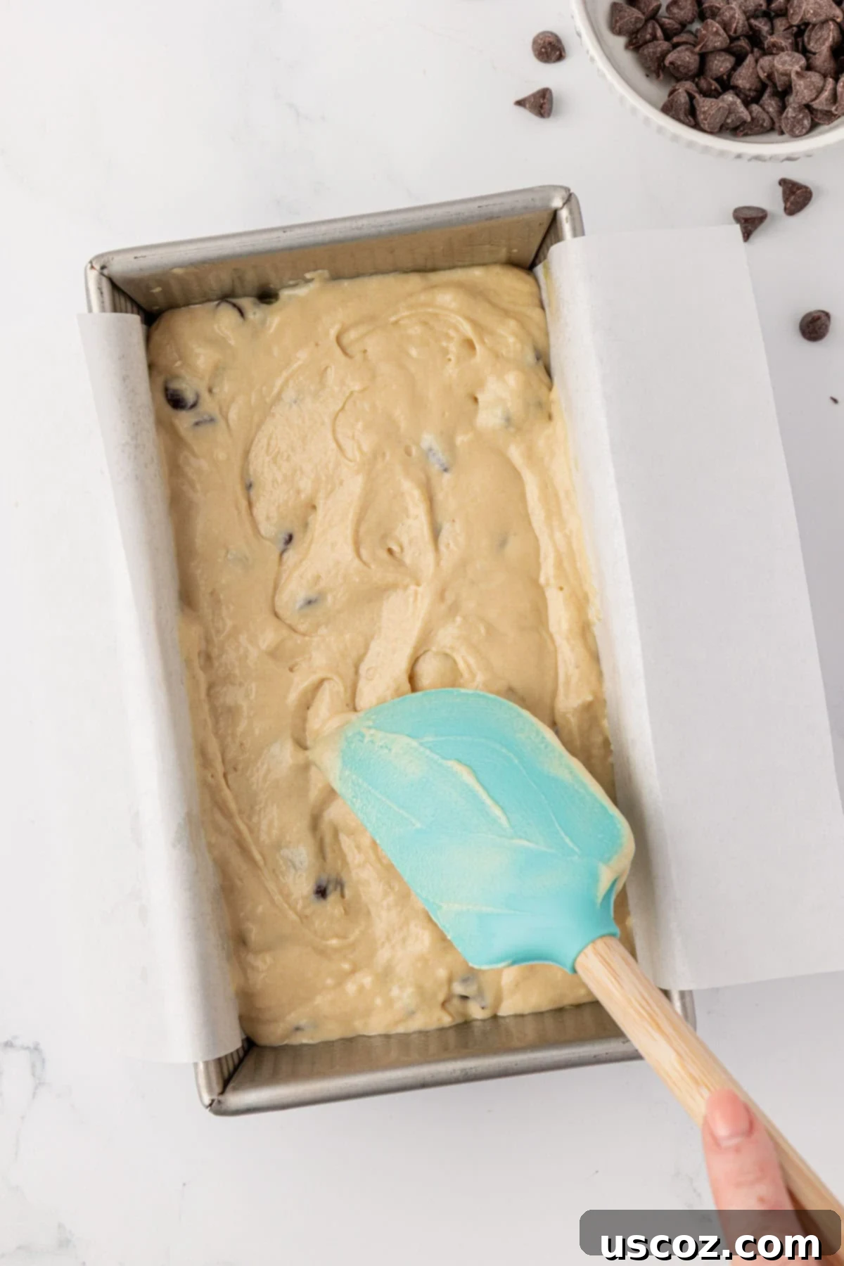 Spreading quick bread batter into a prepared loaf pan