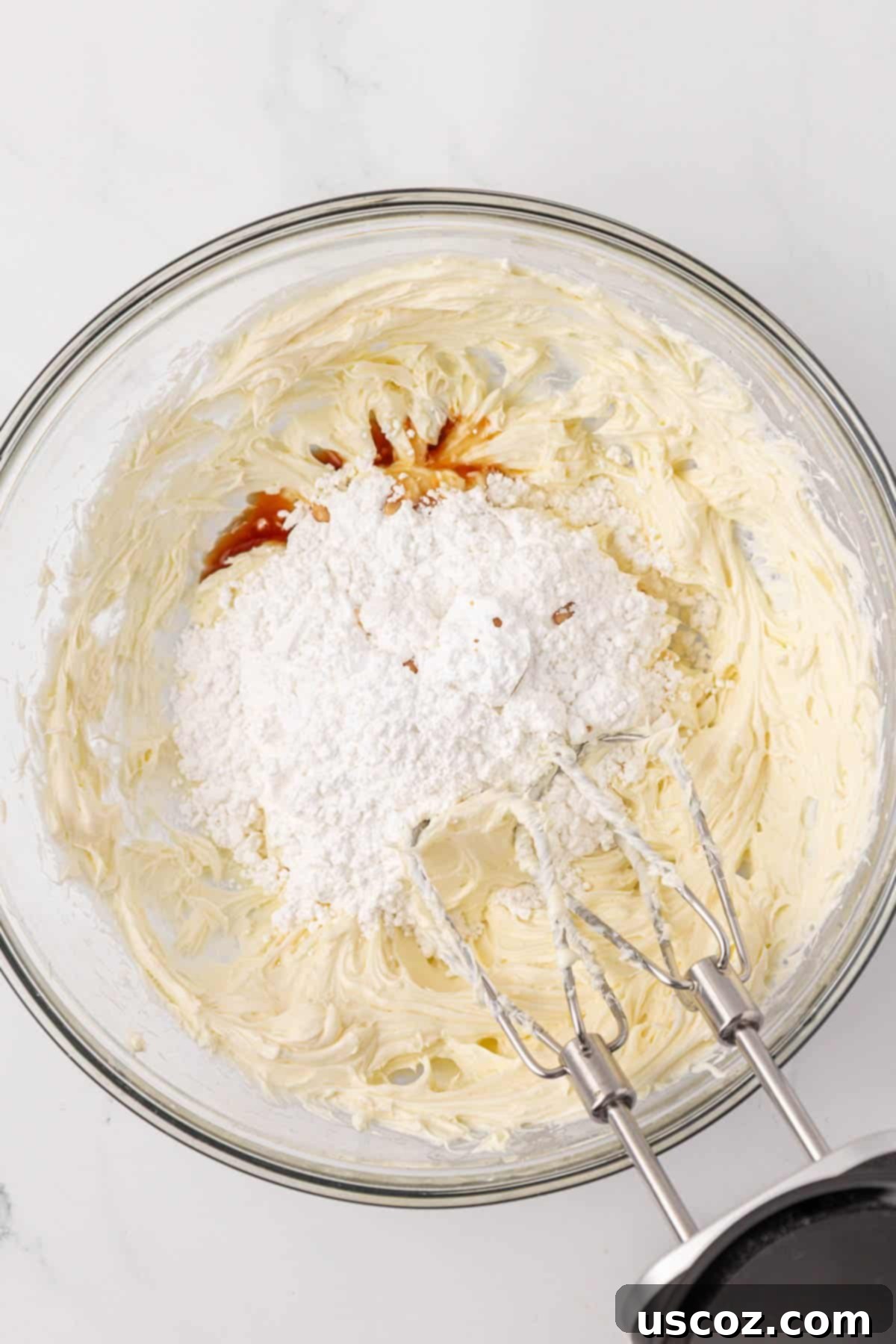 Frosting ingredients including butter, cream cheese, powdered sugar, and vanilla extract in a mixing bowl