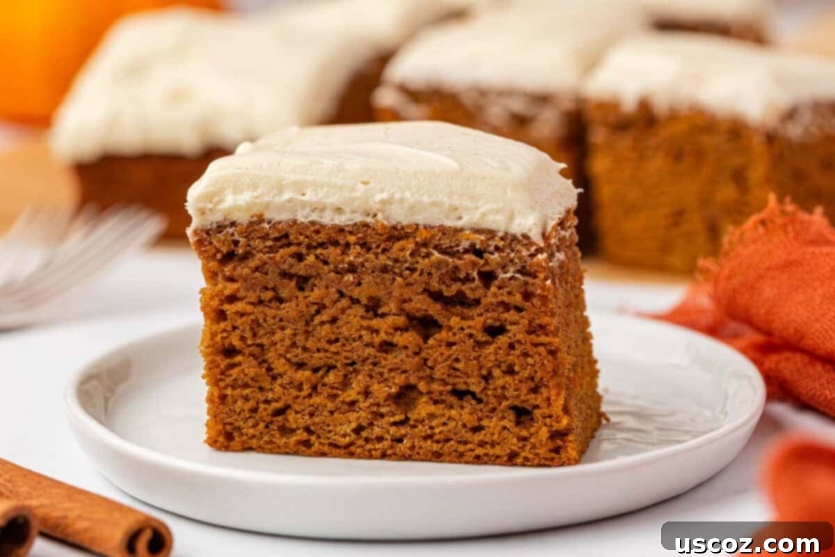 A delectable slice of pumpkin cake with cream cheese frosting on a white plate