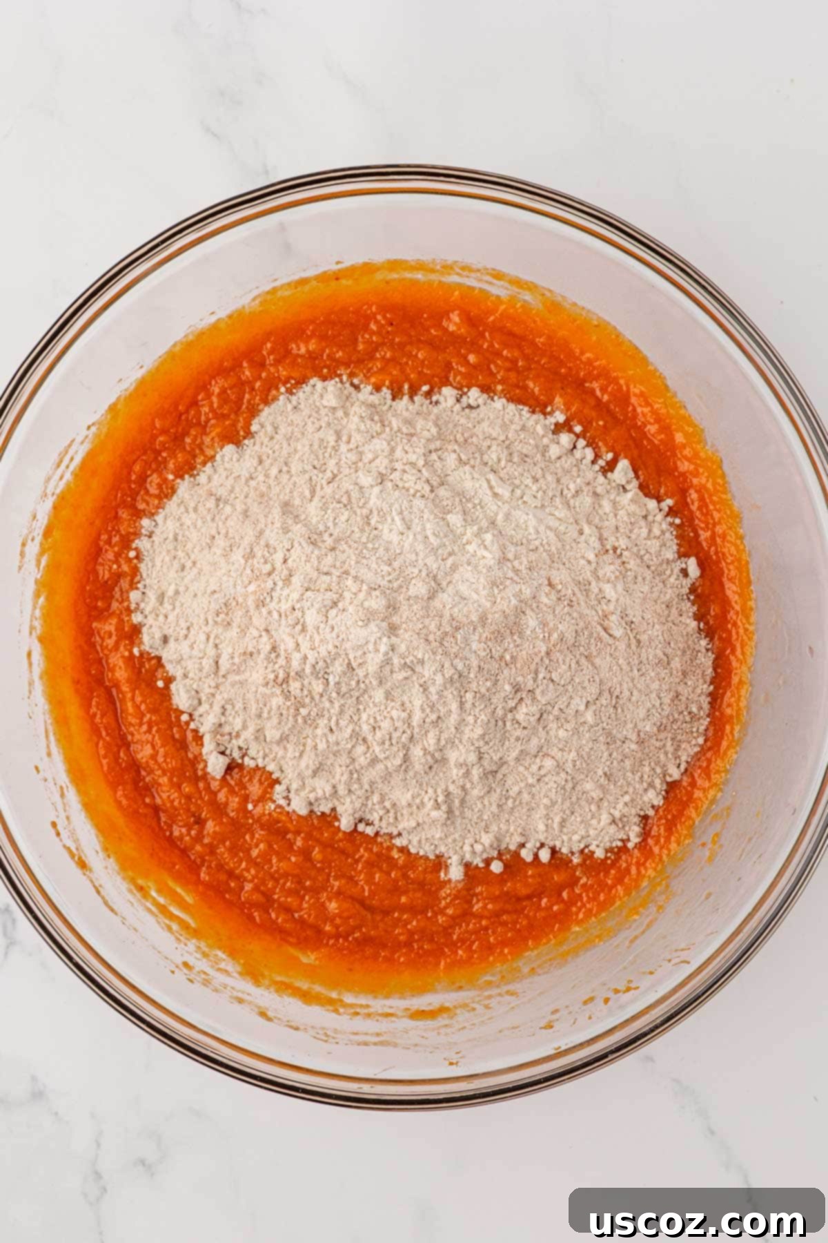 Pouring dry ingredients into wet ingredients for pumpkin snack cake