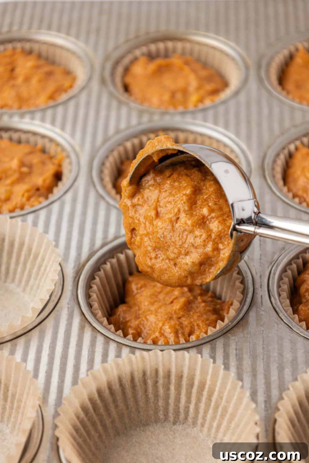 Golden Pumpkin Banana Muffins 13 scooping pumpkin banana muffin batter into a lined muffin tin