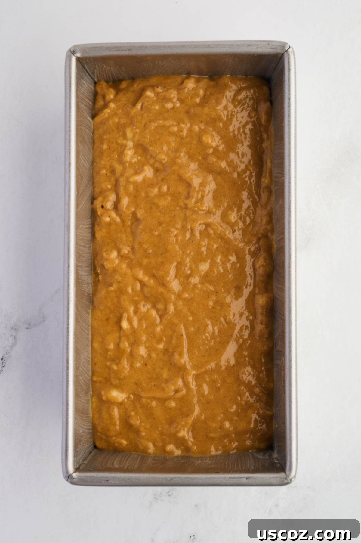 Pumpkin banana bread batter in a greased loaf pan, ready to go into the oven