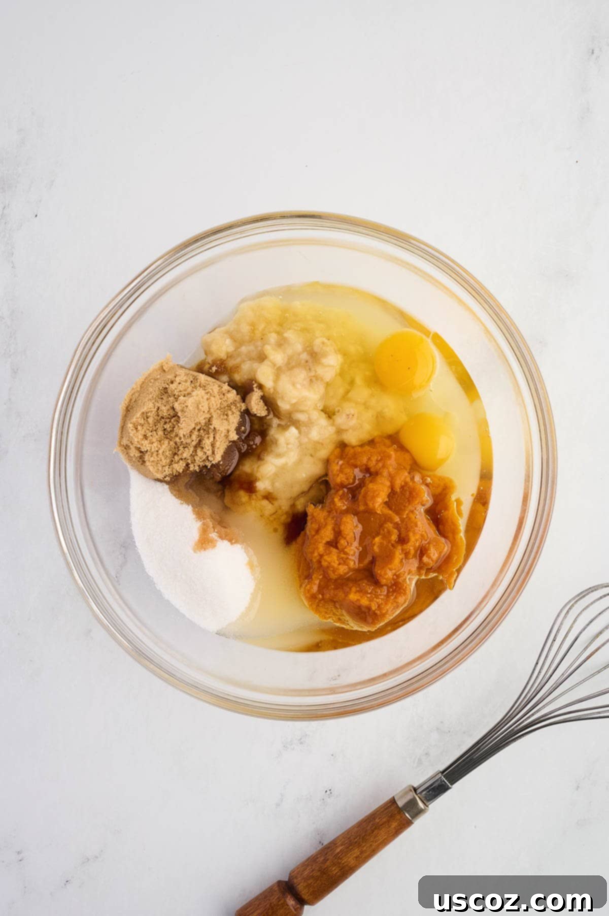 Wet ingredients (mashed bananas, pumpkin puree, oil, eggs, vanilla, sugar) in a mixing bowl before whisking