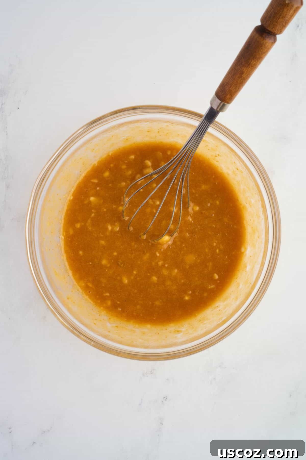 Wet ingredients whisked together in a mixing bowl, creating a smooth and emulsified mixture