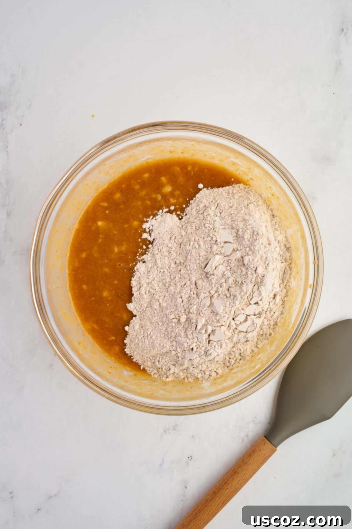Adding dry ingredients to wet ingredients in a mixing bowl, ready to be gently combined